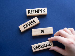 Rethink Revise and Rebrand symbol. Wooden blocks with words Rethink Revise and Rebrand. Businessman hand. Beautiful deep blue background. Business and Rethink Revise and Rebrand concept. Copy space.