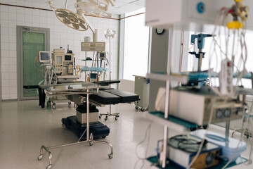 Light interior of modern operating room and equipment in hospital, no people. Medical device for surgeon surgical emergency patient. Light clean surgical theatre with diverse equipment.