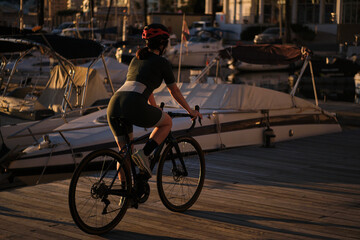 Fit woman cyclist is donned in a complete cycling kit,riding bicycle against the backdrop of a...