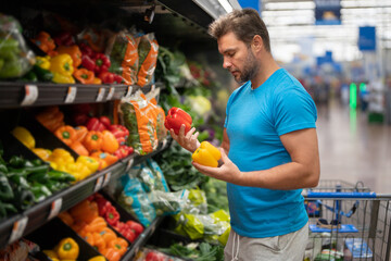 Handsome man with shopping basket with grocery. Man buying groceries in supermarket. Male model in...