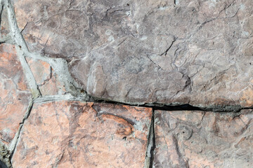 Pattern from natural  pink grey stone blocks for pavement or blind area filled fresh cement solution around private house.