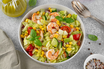 Shrimp salad with vegetables and olive oil mustard dressing. Fresh seafood salad in a bowl on a gray concrete background. Healthy food. Copy space.