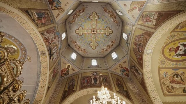 Ornate church ceiling frescoes with a central cross, surrounded by biblical figures and angels. Golden and azure accents enhance the intricate designs, suitable for historical and cultural themes.