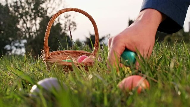 Basket with painted easter eggs, easter egg hunt game theme. Colored eggs in green grass to grab and collect, leisure game on holidays. The religious celebration of Easter.