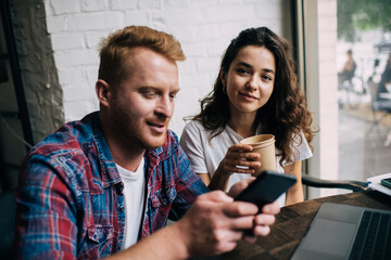 Smiling young friends sitting at table in cafe