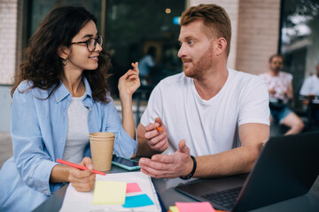 Happy couple discussing and taking notes in clipboard in cafe