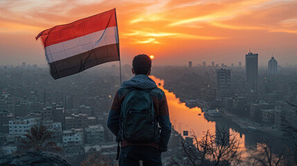 Arabian man with Yemen flag on the background of the sunset and the city.