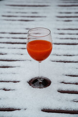 Glass of organic fresh squeezed blood orange juice on a snow covered table at the garden terrace. Healthy eating lifestyle background. Energy shot before winter sport activities - skiing, etc. 