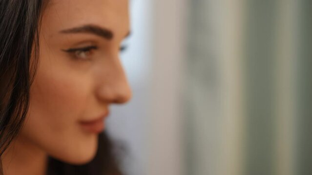 Close-up. Face profile of a beautiful caucasian girl who paints her lips and looks at herself in the mirror