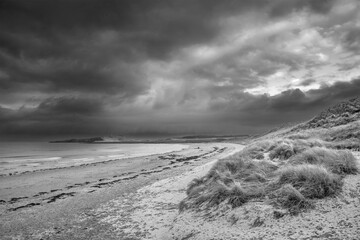 Beautiful dramatic unusual  black and white Winter landscape of snow on Embleton Bay beach in...
