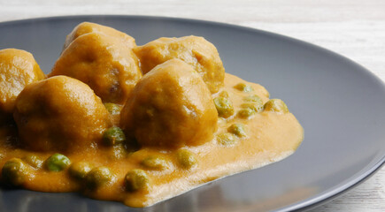 Homemade plate of meatballs with tomato sauce and peas.