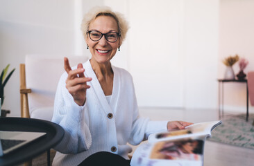 Cheerful senior woman smiling while reading magazine - obrazy, fototapety, plakaty