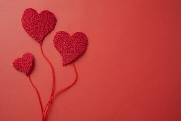 Concept of hearts with threads as if they were balloons on a red background.
