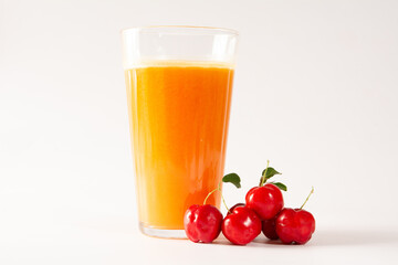 Freshly Harvested Organic Acerolas Juice in a glass with acerolas beside in a clean white background in front view