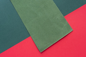 textured green paper rectangle diagonally on dark green and red paper