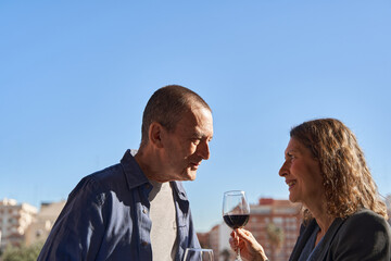 Senior dating concept. Mature male and female in rooftop bar drinking wine and smiling over blue sky with copy space