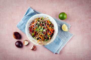Traditional Asian wok spinach with chestnuts, pepper strips and soy sprouts served as top view in a...