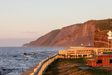 vue sur la mer agitée lors d'un coucher de soleil avec une falaise en arrière plan et une...
