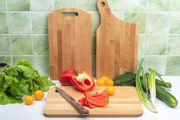 Vegetables and a cutting board with a knife and slicing sweet peppers on the kitchen table.