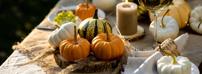 Simple craft elements, pumpkins as decoration, candles. Lunch outdoors in the garden. Cozy dinner table decor for an autumn event, countryside party, thanksgiving dinner or wedding banner