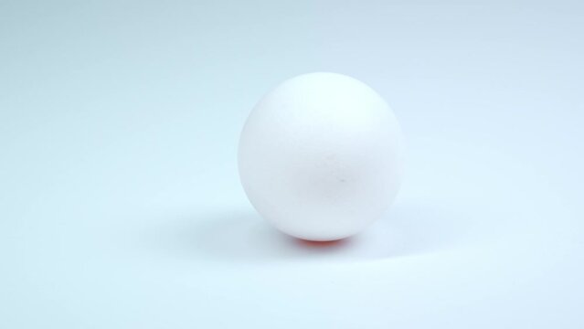 A chicken egg is spinning on a white background