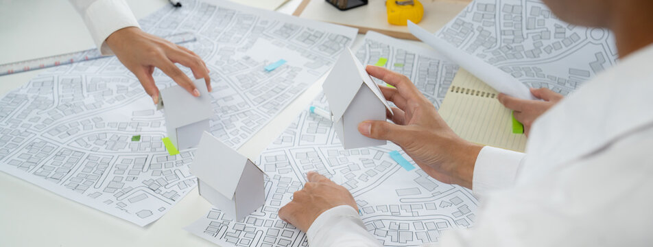 Worker, architect and engineer work on real estate construction project oratory planning with cartography and cadastral map of urban town area to guide to construction developer business plan of city