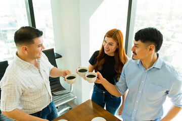 Cheerful office colleagues making a toast with coffee during a work break