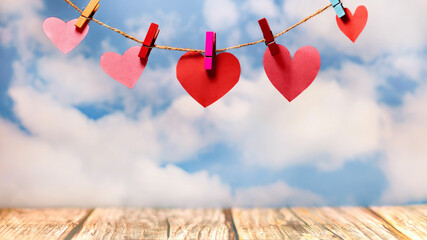 Beautiful and tender hearts hung by wooden clips against a sky background. Greeting card concept...