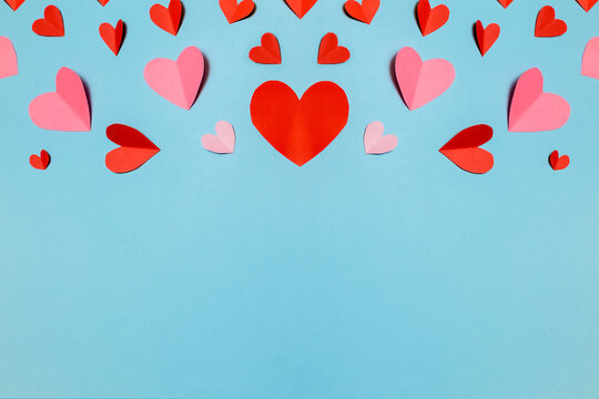 Beautiful pink paper hearts and ribbon arranged on a sky-blue background. Greeting card concept for Valentine's Day. Mother's Day.