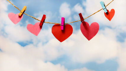 Beautiful and tender hearts hung by wooden clips against a sky background. Greeting card concept...