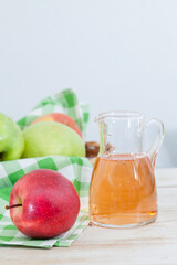 Homemade Apple vinegar in a jarwith red and green apples on the table. Healthy dressing for a salad.