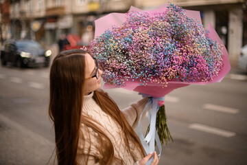 Pretty woman is admiring a huge bouquet of multi-colored gypsophila