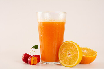 Fresh Organic Acerola and Orange Juice with sliced acerola and orange fruit in a glass cup in white background in front view