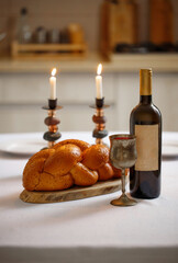 Challah bread, shabbat wine  on the kitchen table. Traditional Jewish Shabbat ritual. Shabbat Shalom.