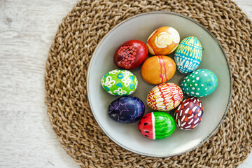 Colorful Easter eggs hand-painted at home. Using food coloring to dye Easter eggs. Painting eggs with candle wax. Getting ready for Easter egg hunt.