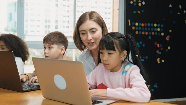 Smart teacher teaching and looking student using laptop at classroom. Professional instructor explained about programing engineering code or prompt while studying and learning program. Erudition.