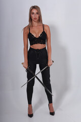 Pretty blonde woman in black lingerie holding two old swords crossed