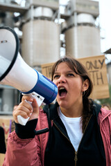 Vertical. Angry and rebellious woman speaking and protesting with megaphone at demonstration at climate change and global warming. Group of activists people at a pro-earth manifestation with banners