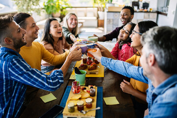 Smiling multiracial group of young people having breakfast together at coffee eatery shop