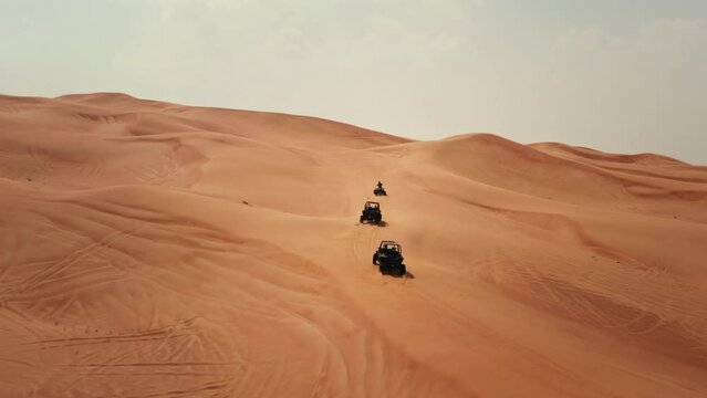 Aerial view of tourists riding dune buggies and quad bike in Dubai desert dunes UAE