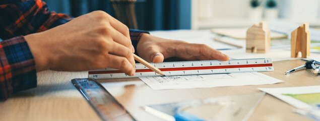 Closeup of architect engineer hand using ruler to mature and draw a blueprint on meeting table with...