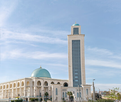 The Ibn Badis mosque in Cite Djamel, Oran, Algeria. Domes and minaret in turquoise blue color with golden spikes and crescent moon in a sunny day with blue sky with clouds. 
