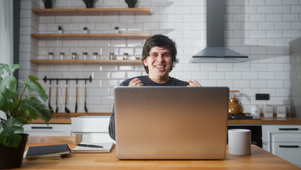 Overjoyed young man sitting in the kitchen checking messages read notice receive good news on laptop in e-mail celebrate great opportunity feels happy	 - obrazy, fototapety, plakaty