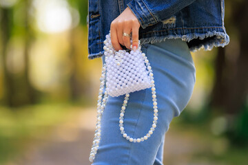 A stylish handbag in the hands of a young woman. Background with selective focus and copy space
