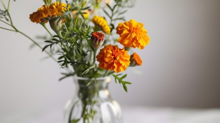 Fototapeta premium a vase filled with yellow and orange flowers on top of a white tablecloth and a white wall behind the vase is a gray wall behind the vase is a.