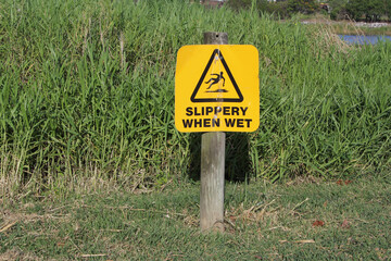 Yellow "Slippery When Wet" sign surrounded by green grass