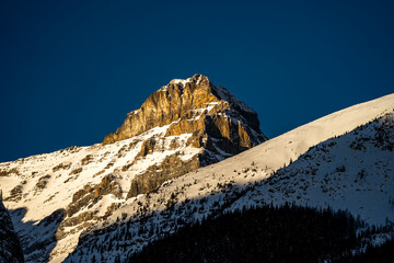 mountain peak lightly covered in snow during golden hour