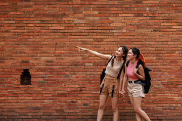 two asian tourist girl standing posing and pointing hand at the tha phae gate, chiang mai thailand,