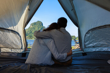 caucasian couple sitting inside a tent on a camping trip,