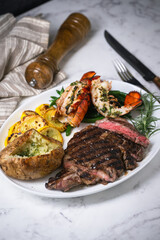 surf and turf, ribeye steak and lobster tail on white marble background